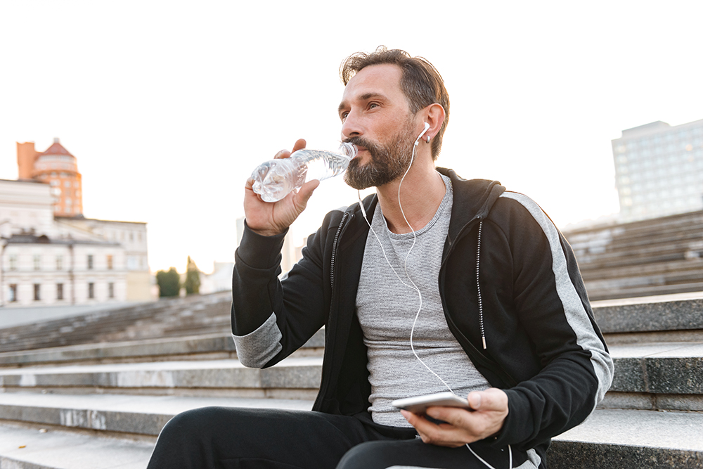 Attractive sportsman in earphones holding mobile phone