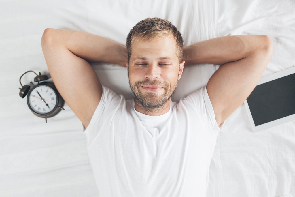 Man sleeping on bed after using his digital tablet