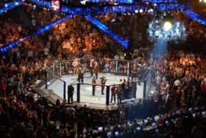 UFC Octagon during a UFC event with a large crowd and TV broadcast crew.