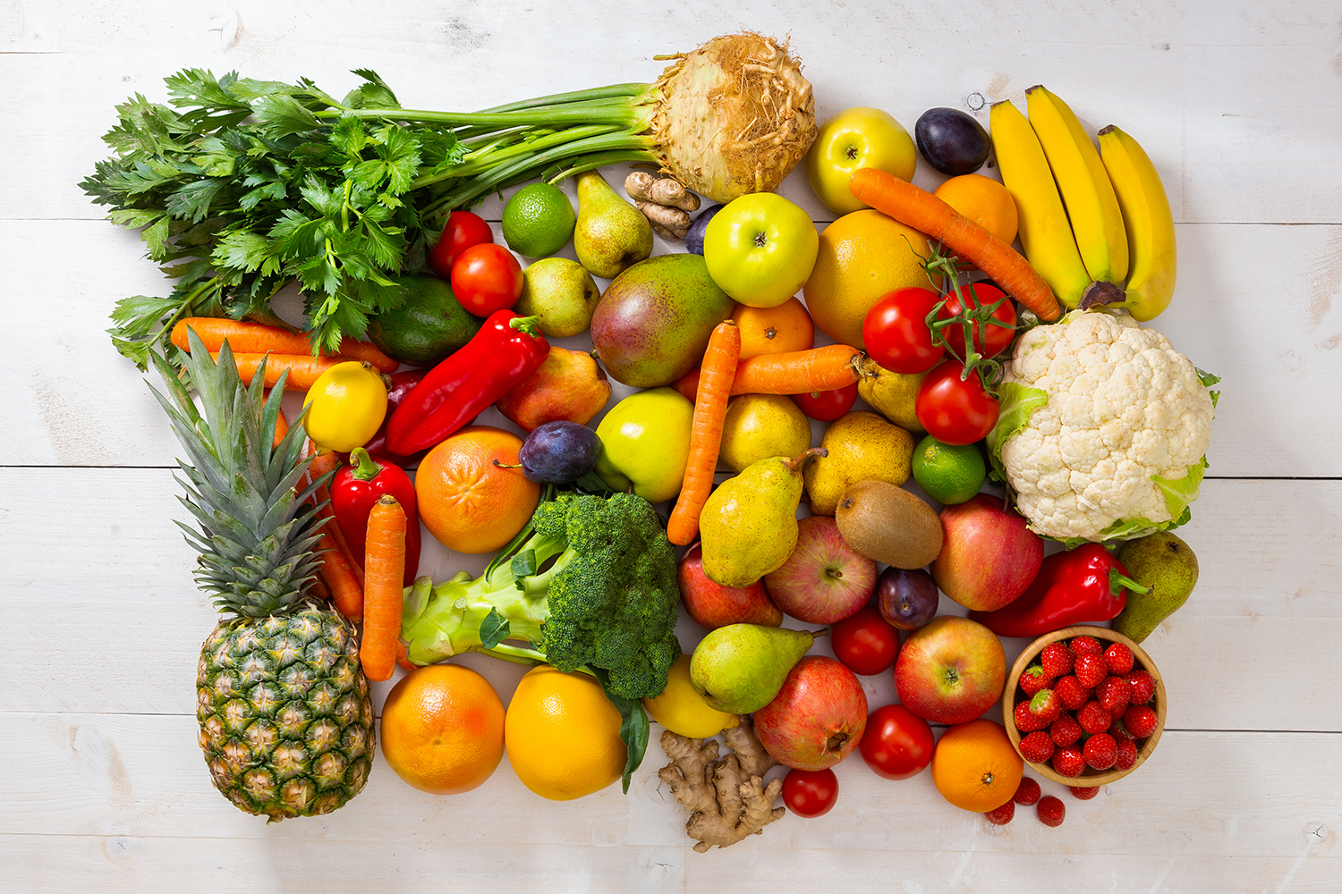 Assorted fruit and vegetable on white wood background. Heap of fresh healthy juicy fruit on wooden desk. Many colorful raw nutrition plants in woody frame.